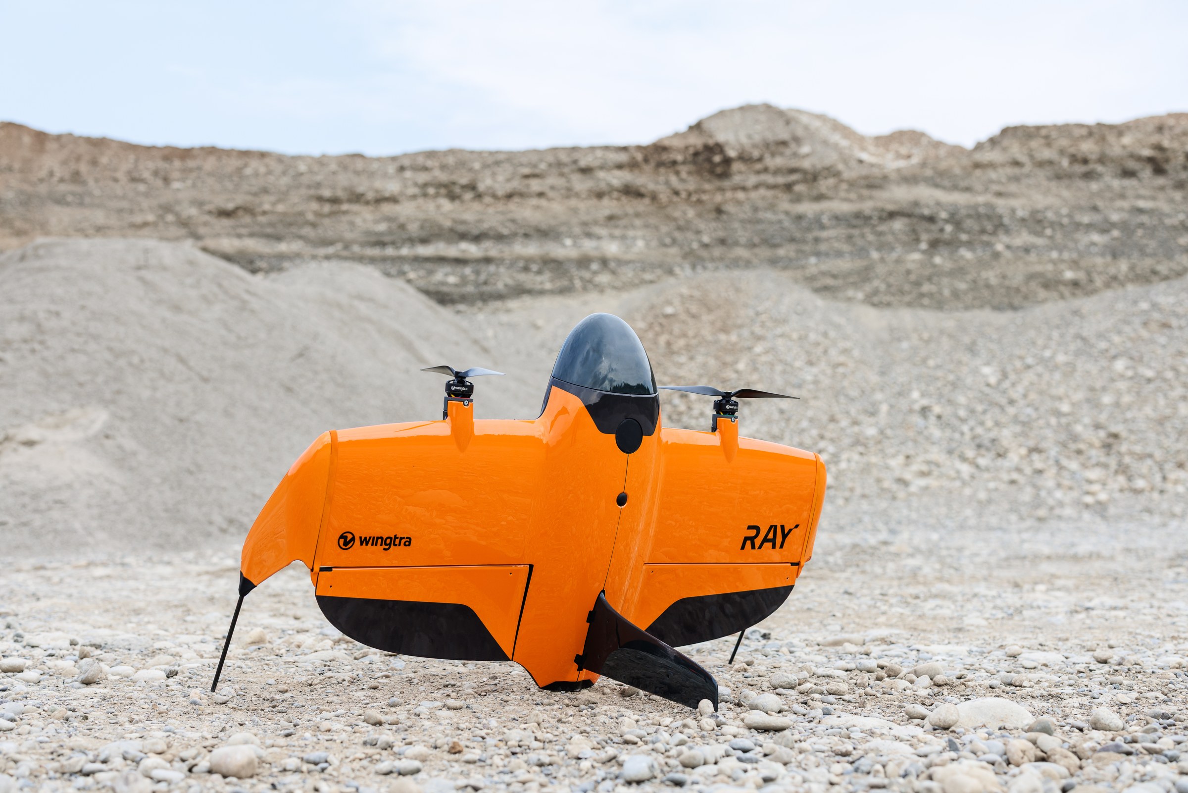 Orange Wingtra RAY aircraft standing on its landing supports in a quarry